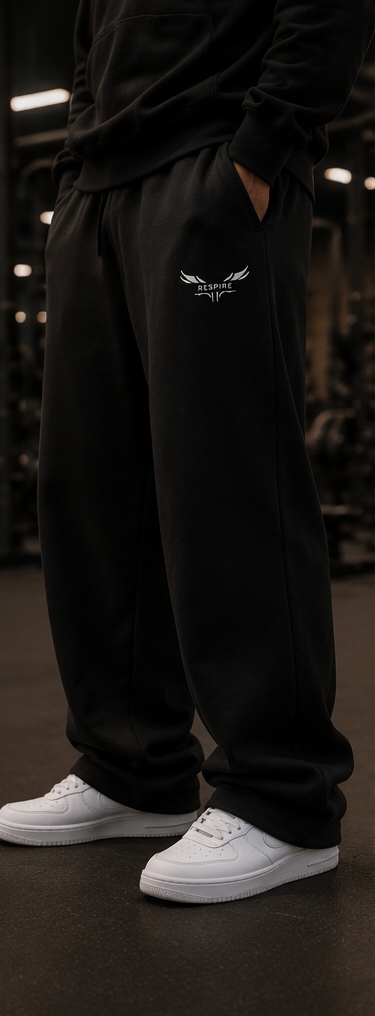 Person wearing Respire Alpine Sweats in black with a relaxed fit and logo, paired with white sneakers.